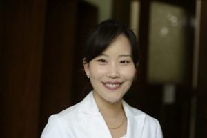 A headshot of SJ Claire Hur wearing a white suit.